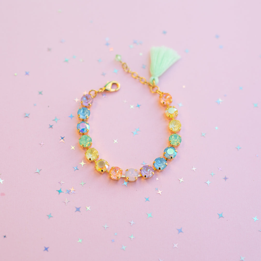Colorful beaded bracelet with a tassel on a pink background