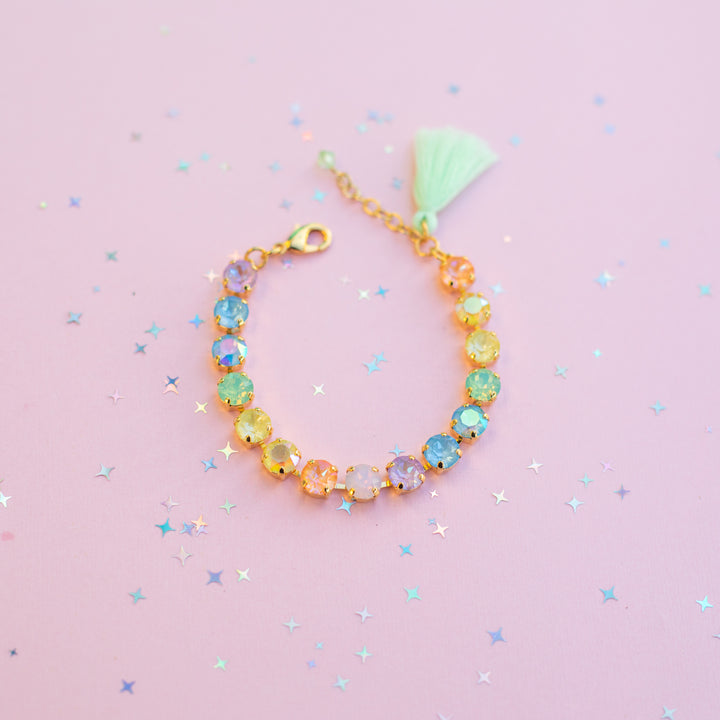 Colorful beaded bracelet with a tassel on a pink background
