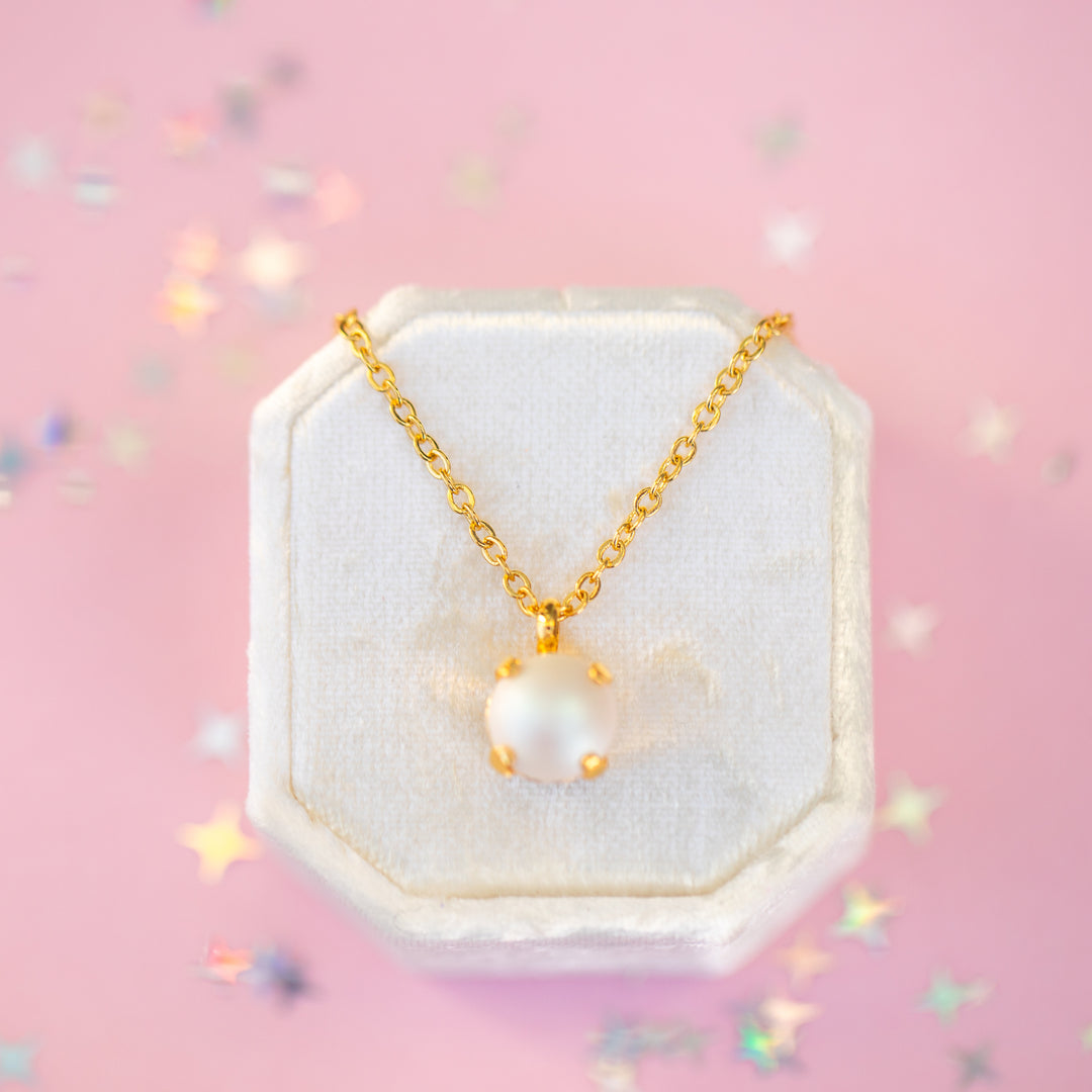 Pearl necklace on a hexagonal white stand with a pink background