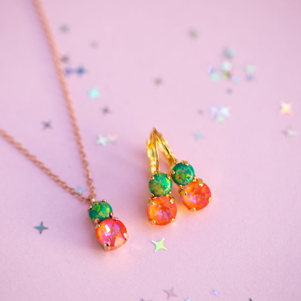 Colorful gemstone earrings and necklace on a pink background with star-shaped glitter.