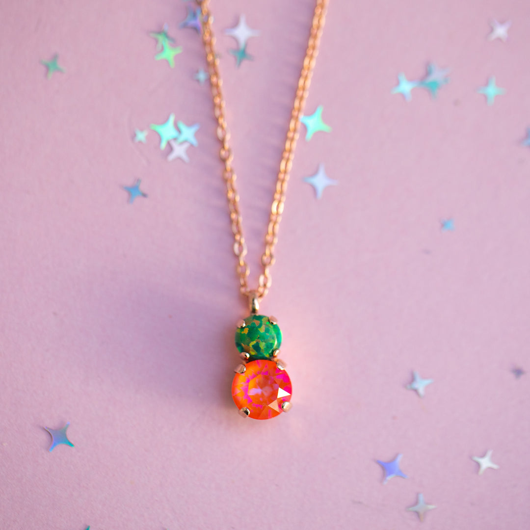 Necklace with colorful pendant on a pink background with star shapes