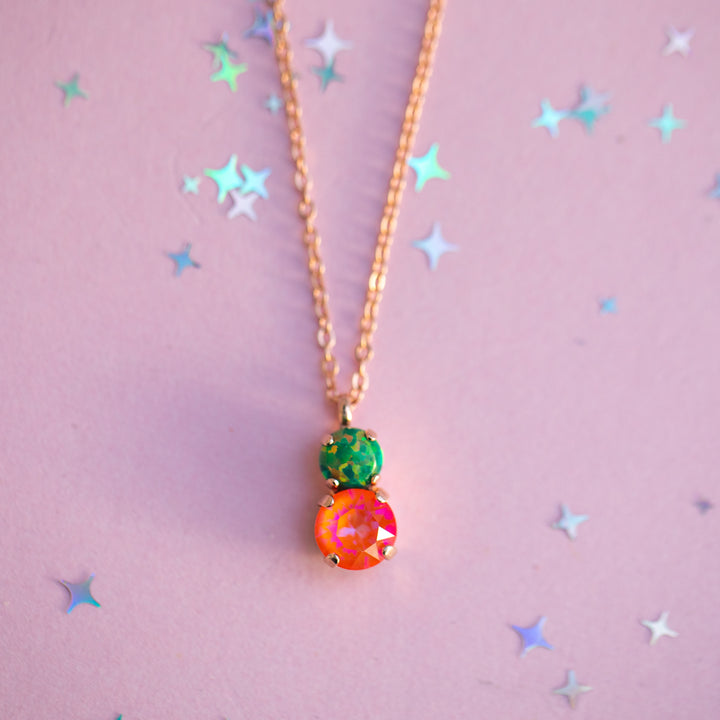 Necklace with colorful pendant on a pink background with star shapes