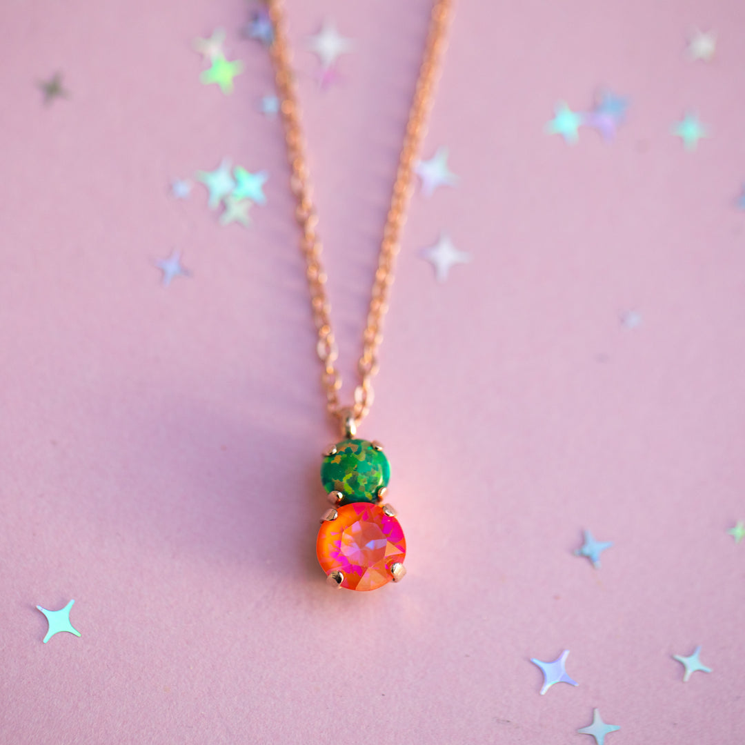 Necklace with a colorful pendant on a pink background with star-shaped decorations