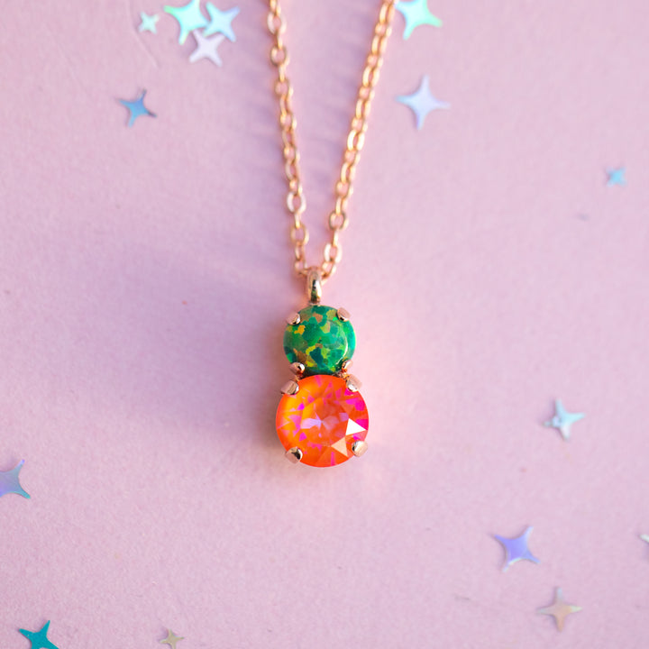Necklace with colorful pendant on a pink background with star shapes