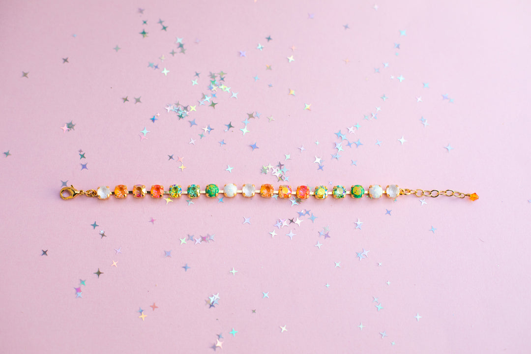 Multicolored beaded bracelet on a pink background with star-shaped confetti