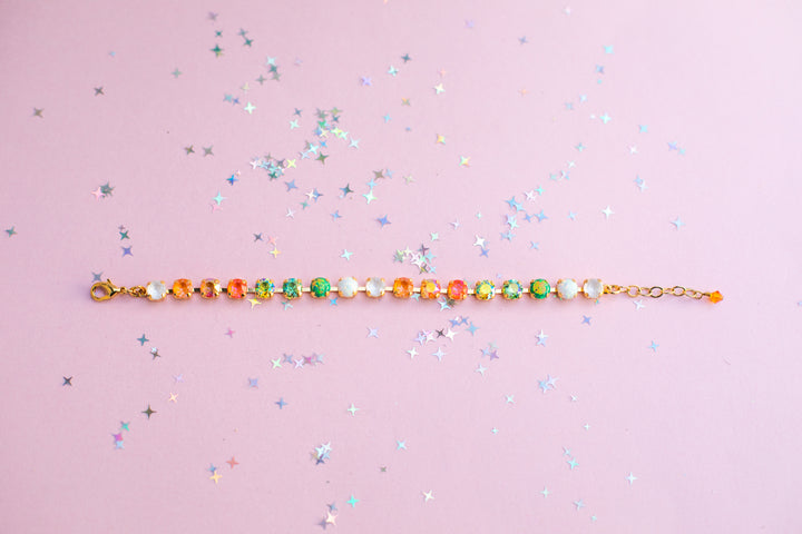 Multicolored beaded bracelet on a pink background with star-shaped confetti