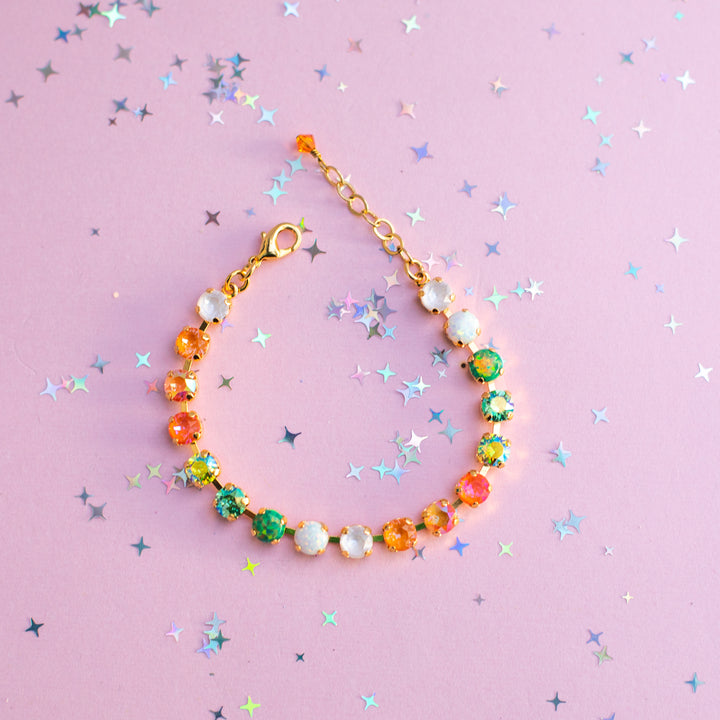 Colorful beaded bracelet on a pink background with star-shaped confetti