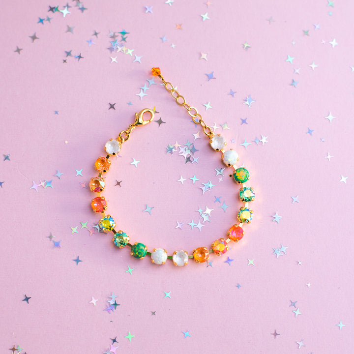 Colorful beaded bracelet on a pink background with star-shaped confetti