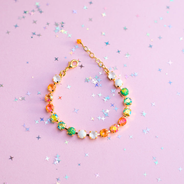 Colorful beaded bracelet on a pink background with star-shaped confetti
