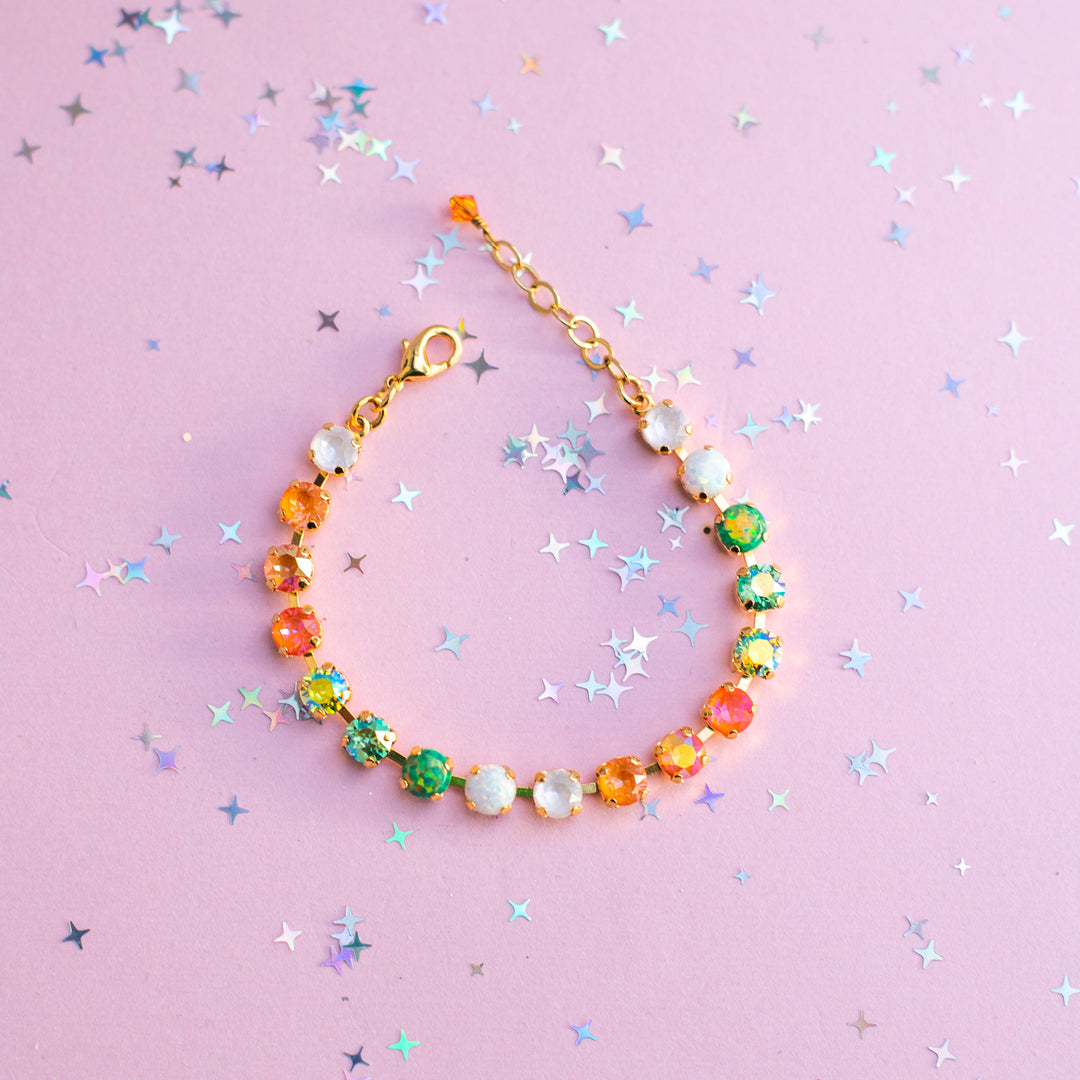 Colorful beaded bracelet on a pink background with star confetti