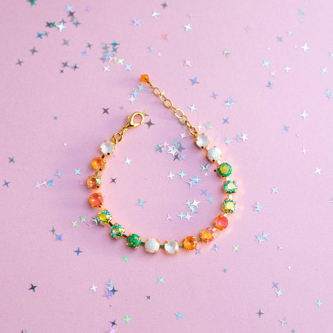 Colorful beaded bracelet on a pink background with star-shaped confetti