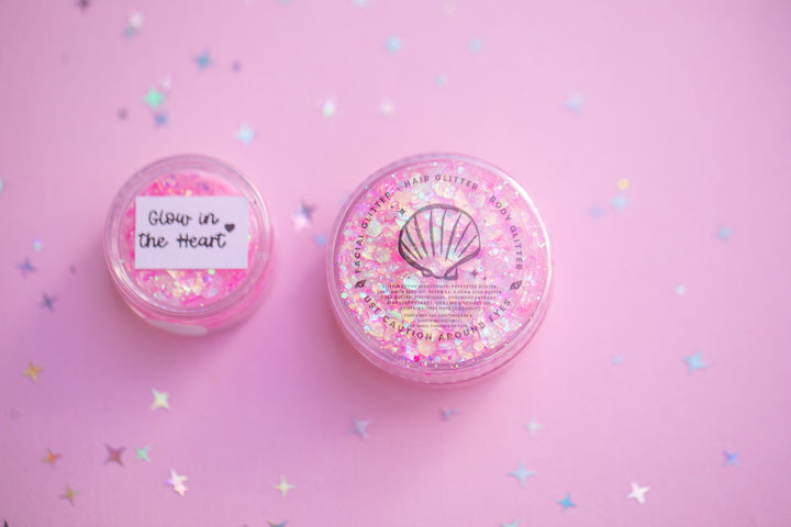 Two pink glittery containers with labels on a pink background