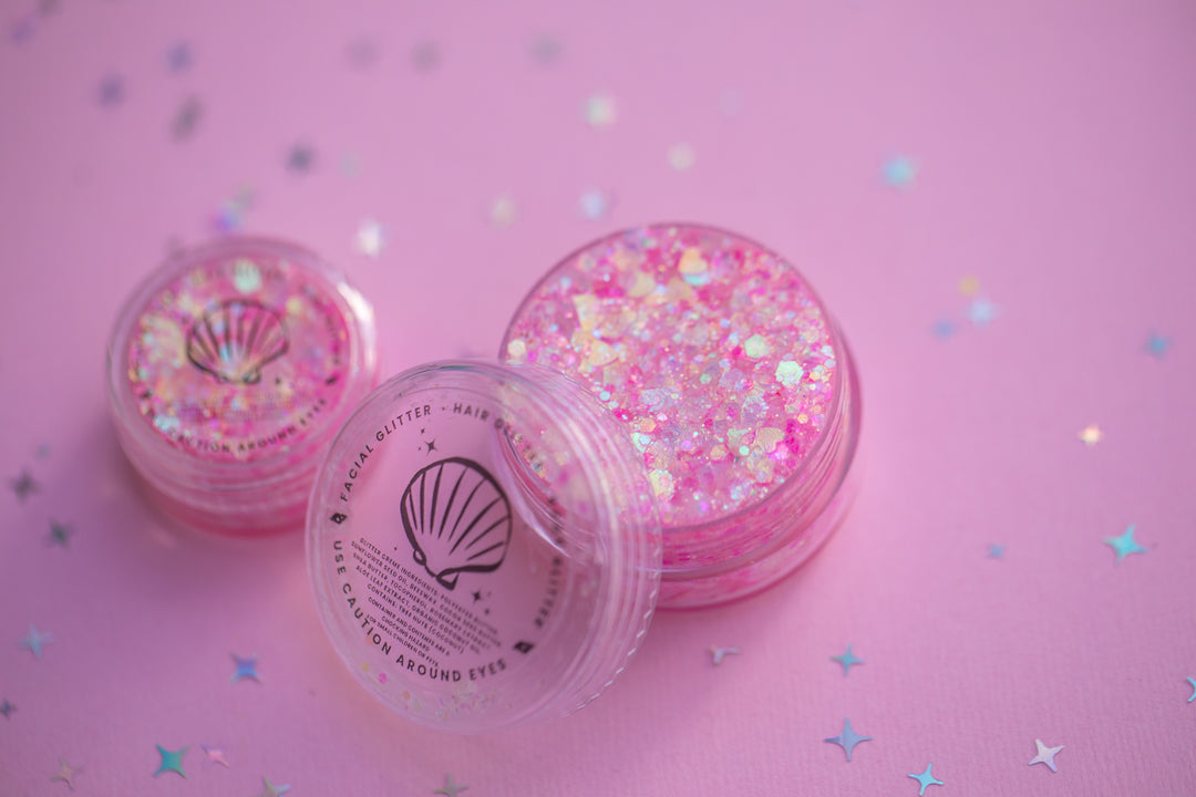 Pink glitter containers on a pink background with star patterns