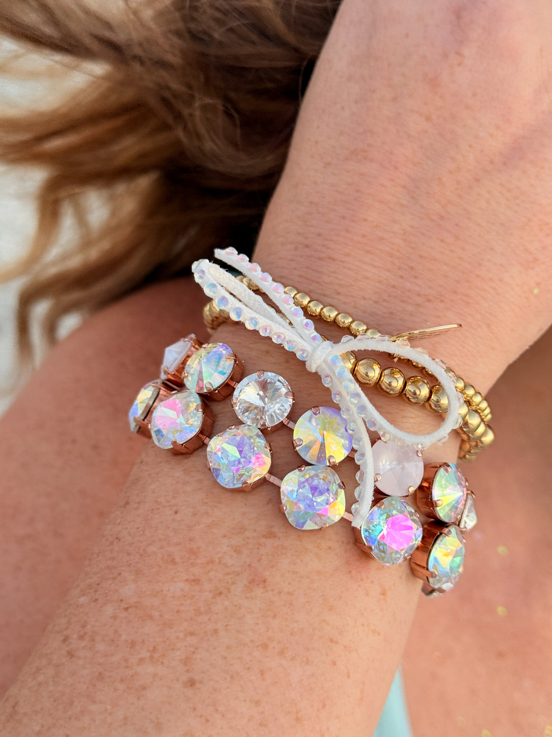 Close-up of a wrist wearing multiple beaded bracelets with iridescent beads.