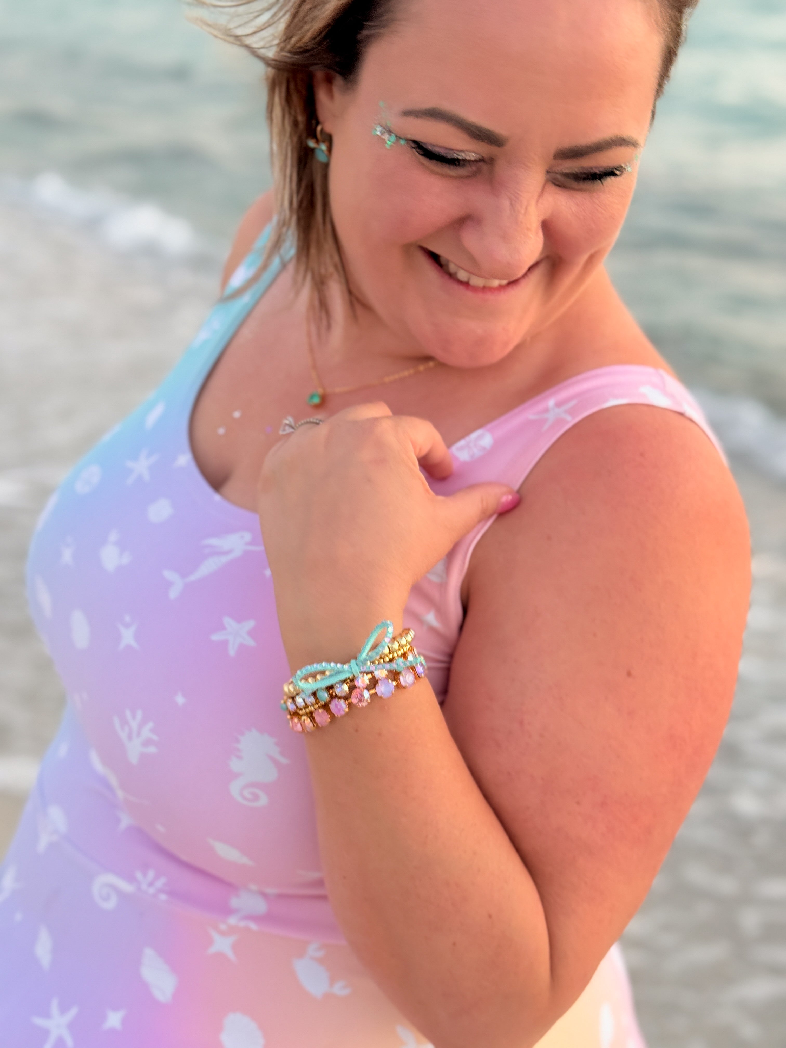 Woman on a beach wearing a colorful dress and multiple bracelets.