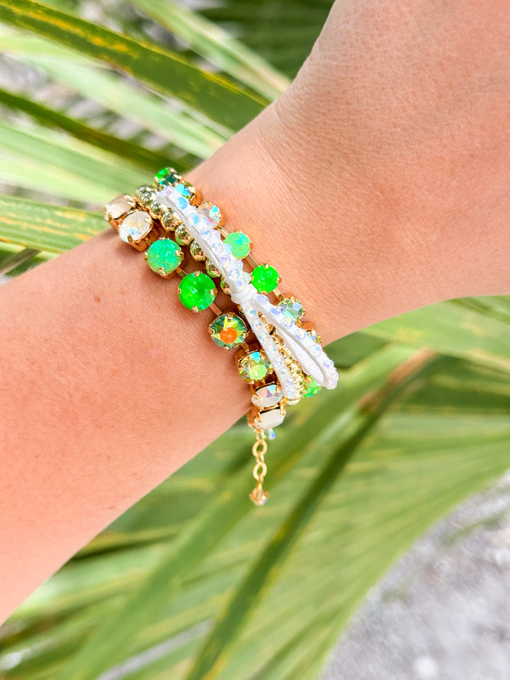 Bracelet with green and gold beads on a wrist against a natural background