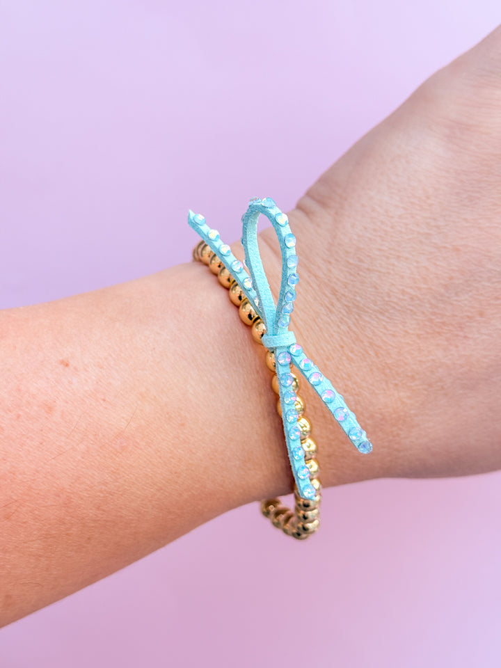 Mint blue beaded bracelets on a wrist against a light purple background