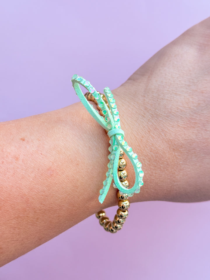 Mint green beaded bracelet on a wrist with a purple background