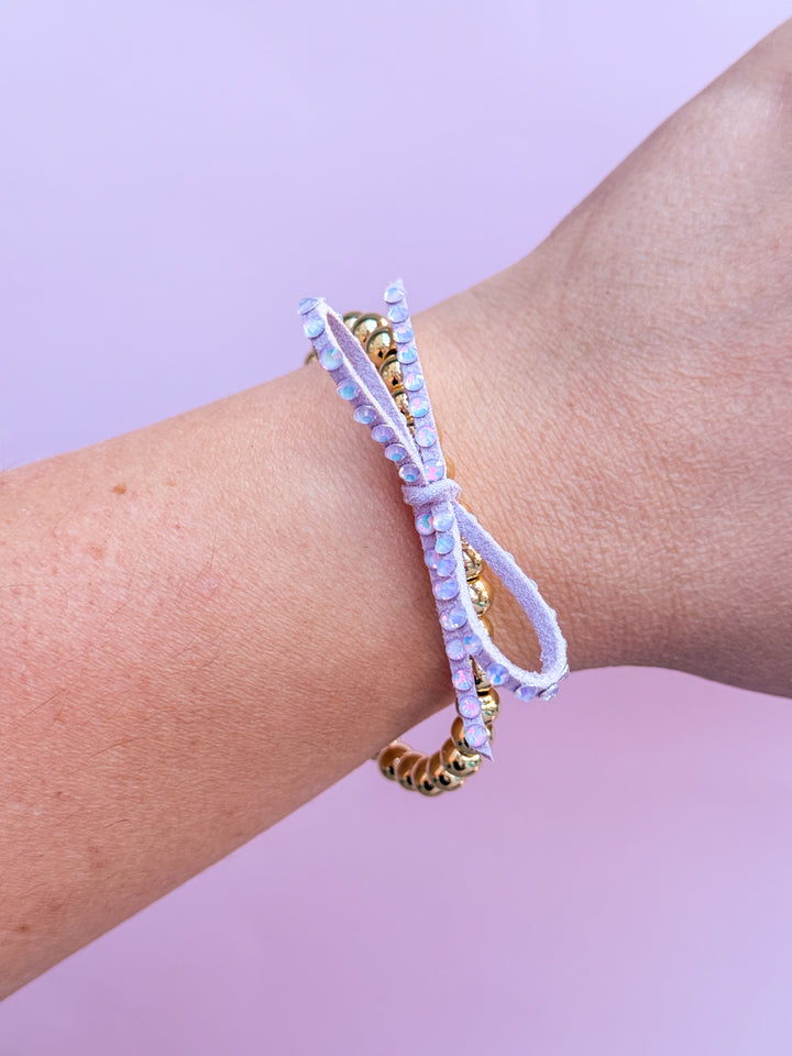 Light Purple beaded bracelets on a wrist against a light purple background