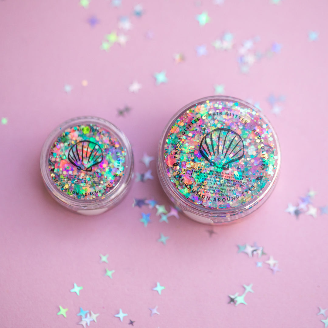 Two containers of glitter with a shell design on a pink background with star-shaped confetti.