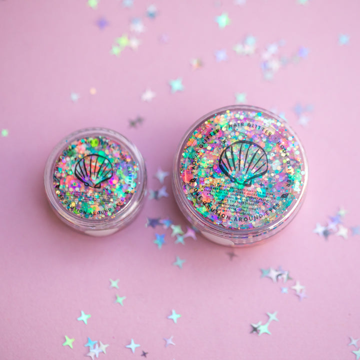Two containers of glitter with a shell design on a pink background with star-shaped confetti.