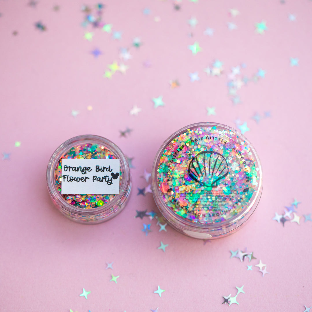Two glitter jars with colorful confetti on a pink background