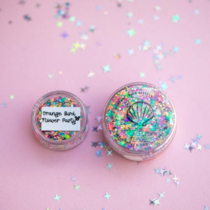 Two glitter jars with colorful confetti on a pink background