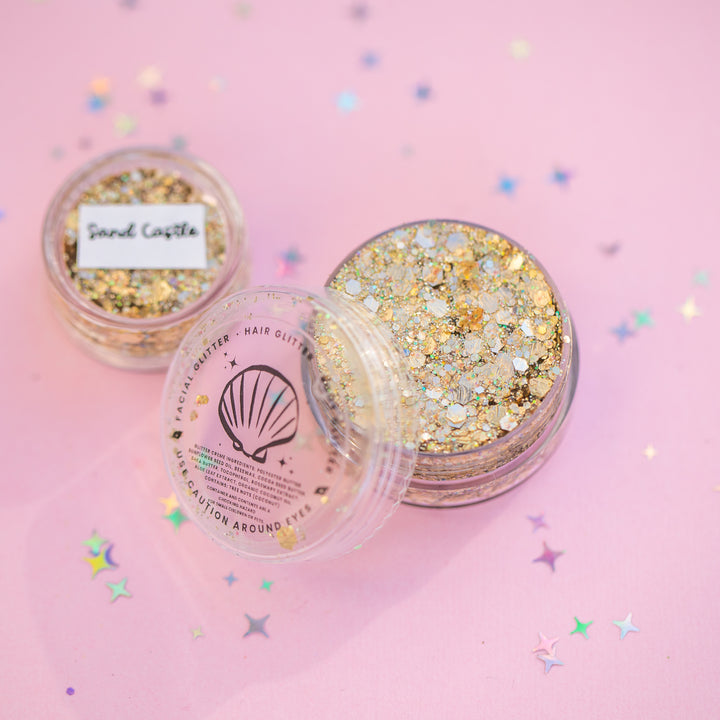 Three containers of glitter on a pink background with confetti
