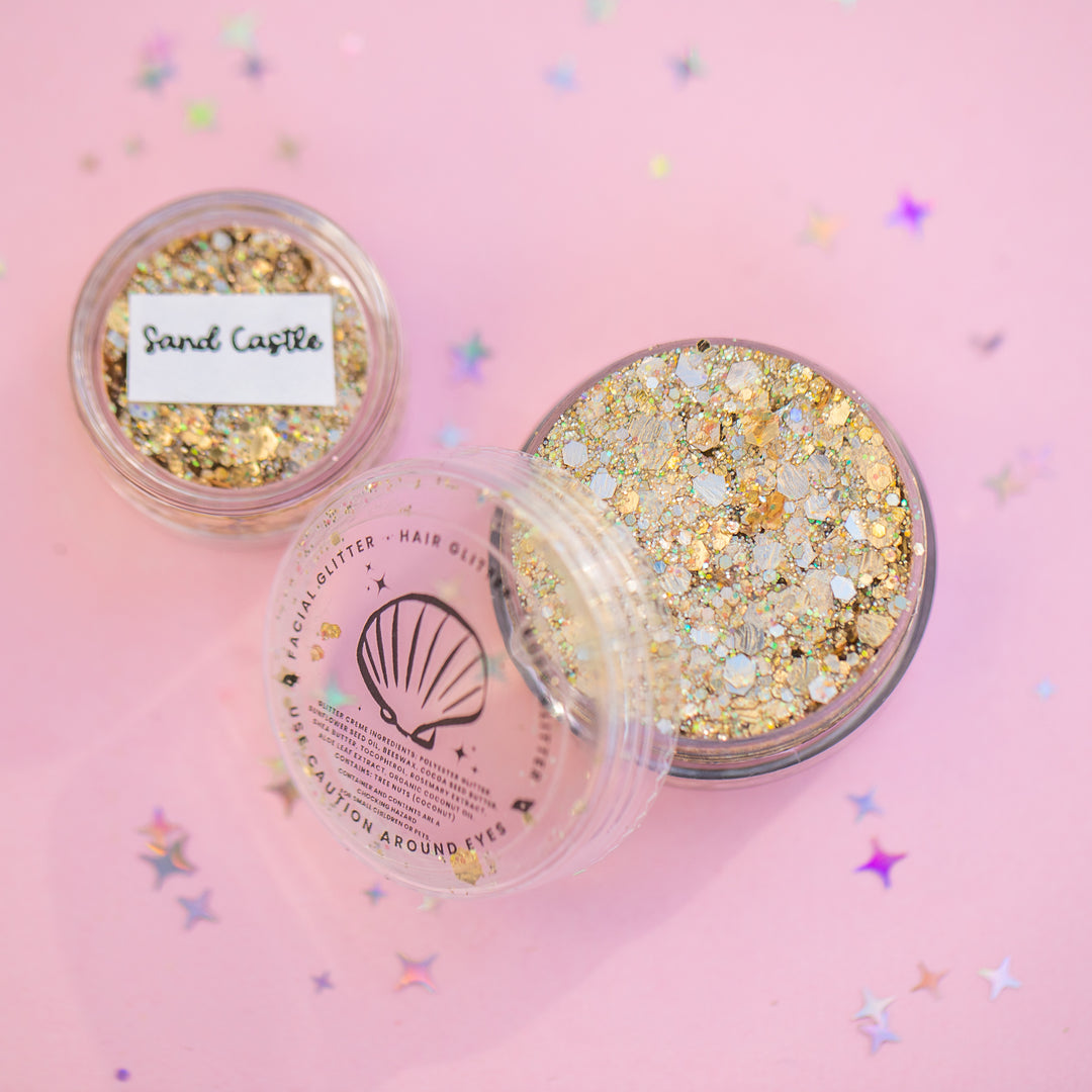 Two containers of glitter on a pink background with confetti