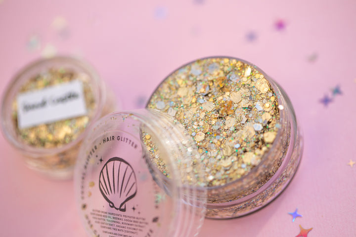 Gold glitter in a jar with a pink background
