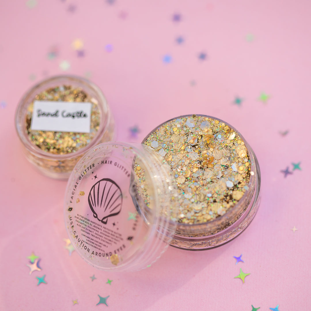 Two containers of glitter on a pink background with star-shaped confetti.