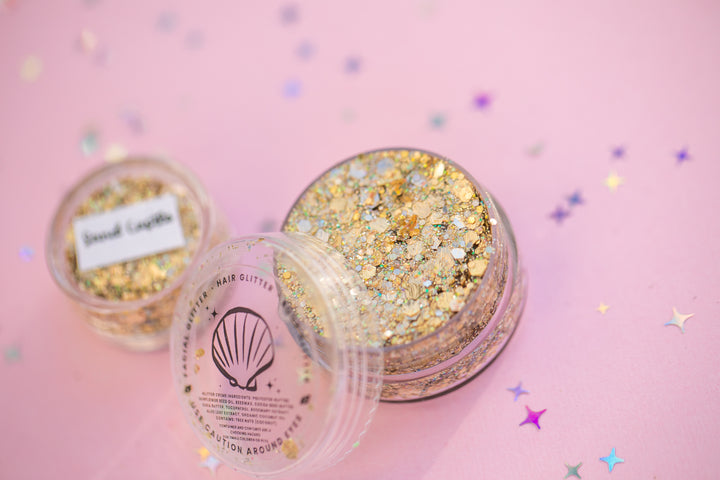 Gold glitter in a container with a pink background