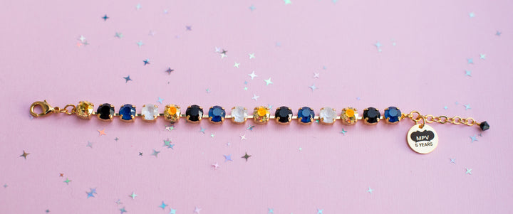 Multicolored beaded bracelet with a heart-shaped tag on a pink background