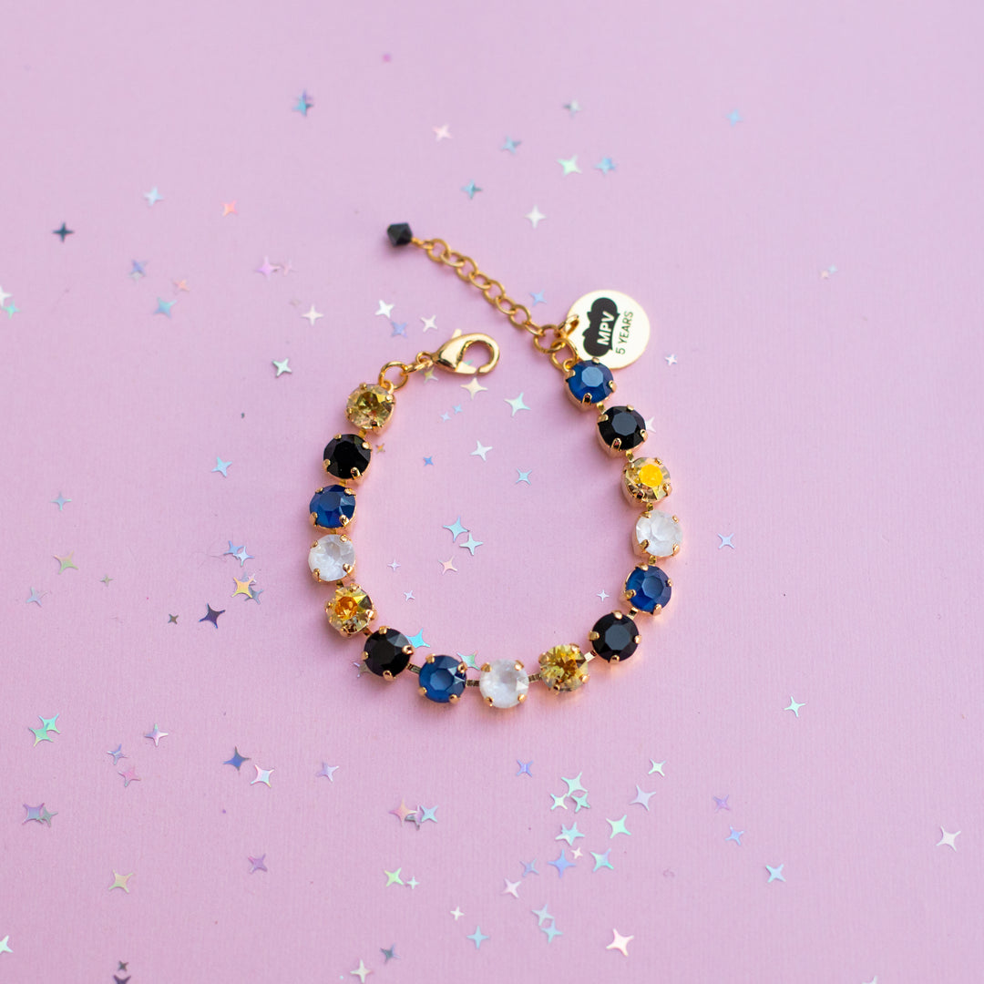Multicolored beaded bracelet on a pink background with star-shaped confetti