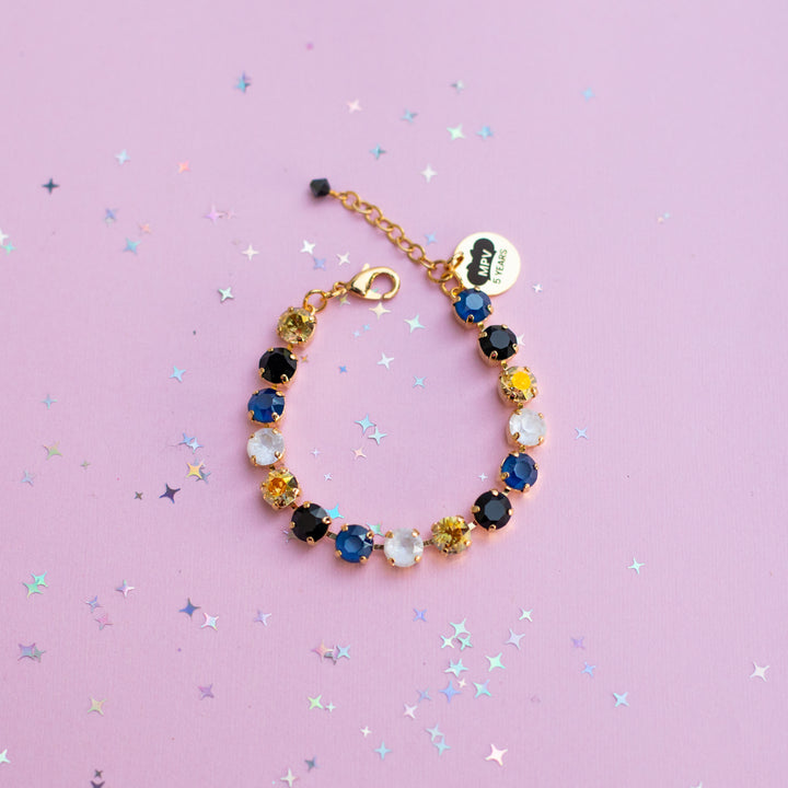 Multicolored beaded bracelet on a pink background with star-shaped confetti