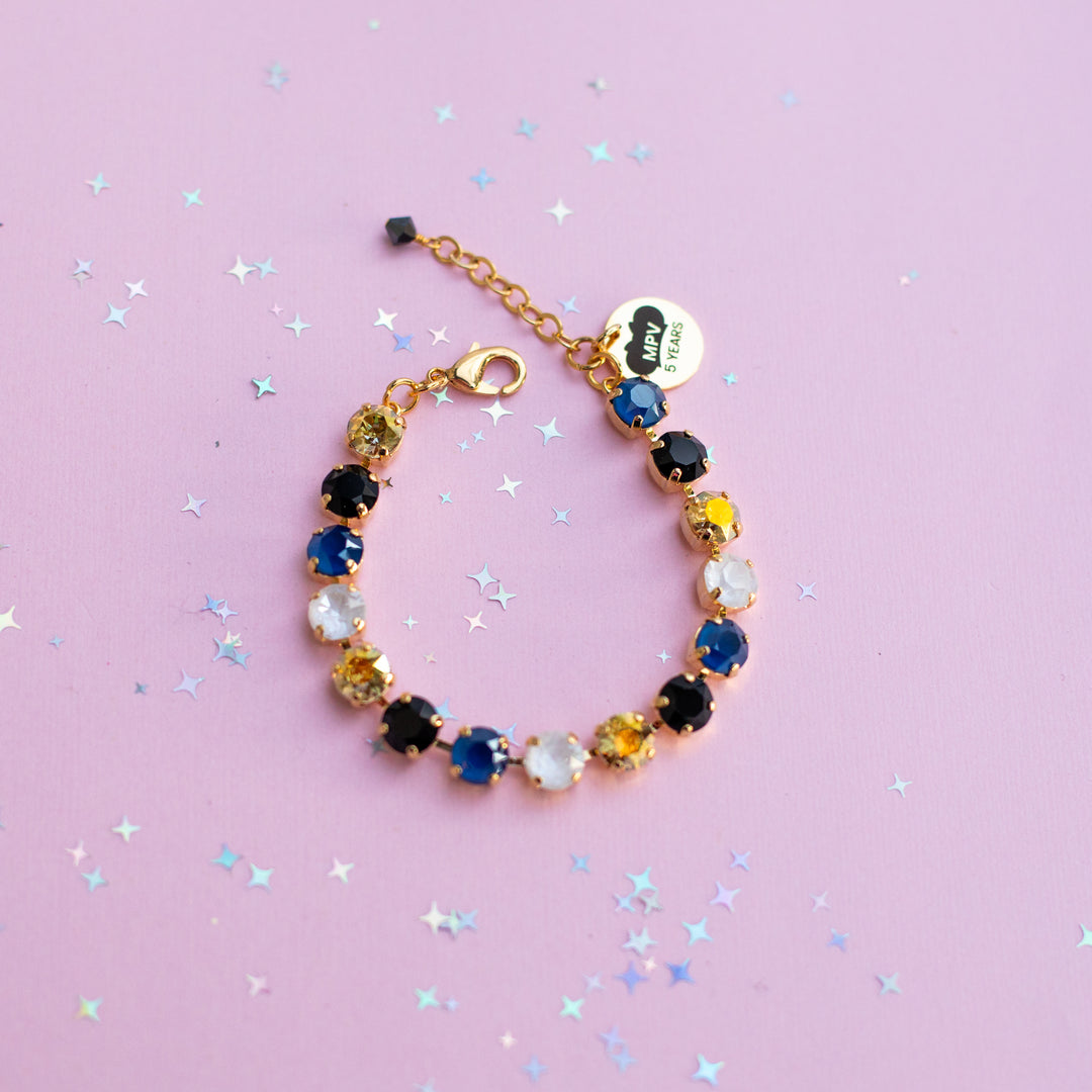 Multicolored beaded bracelet on a pink background with star-shaped confetti
