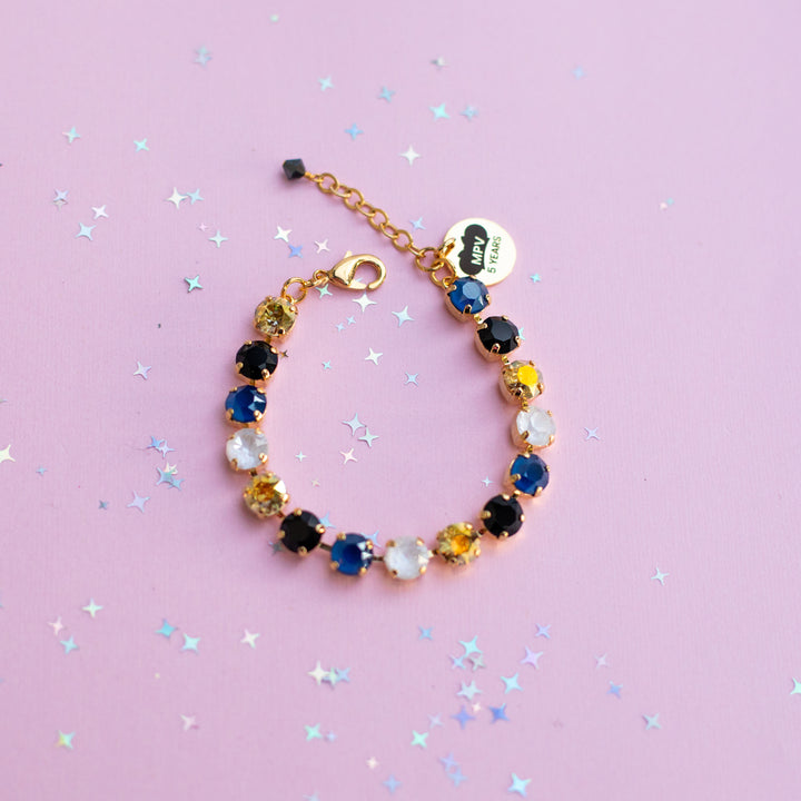 Multicolored beaded bracelet on a pink background with star-shaped confetti