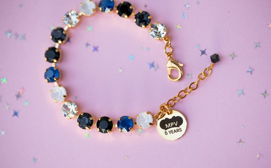 Bracelet with gemstones and a gold charm on a pink background