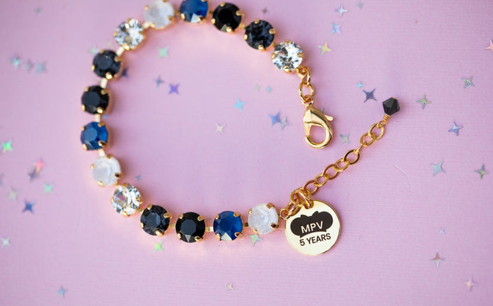 Bracelet with gemstones and a gold charm on a pink background