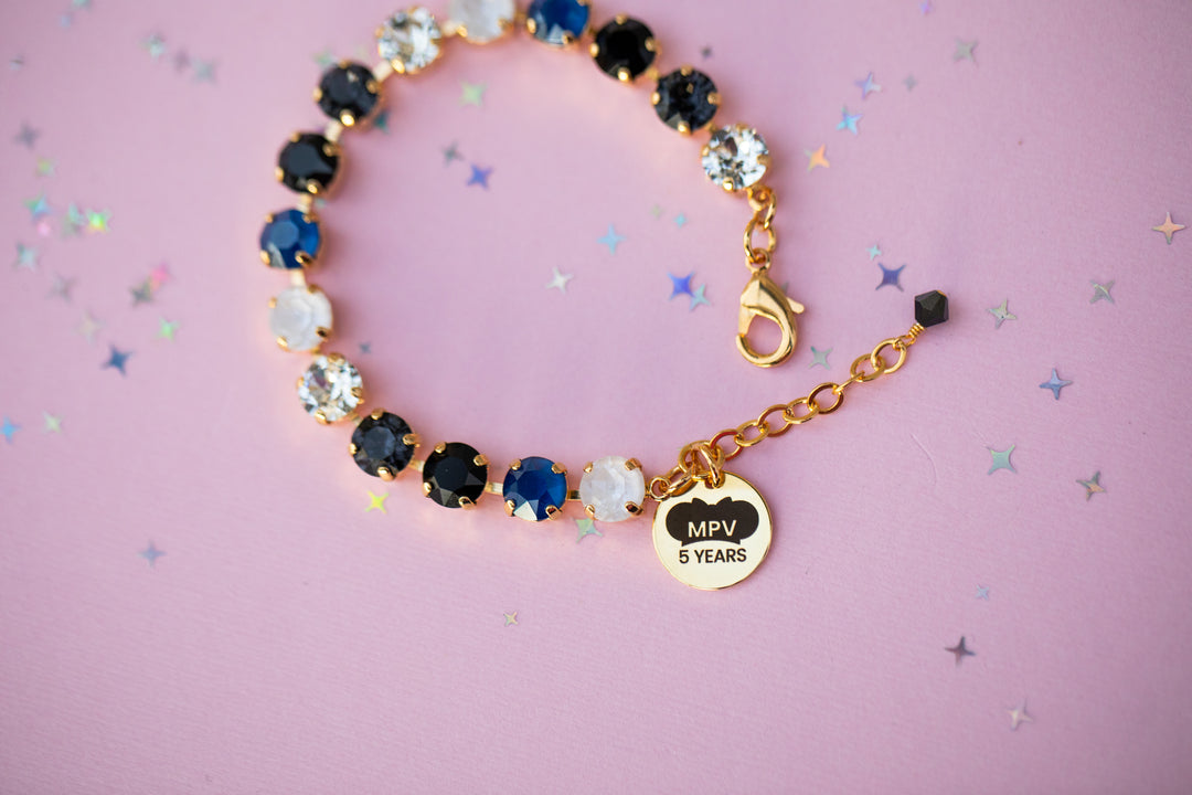 Bracelet with colorful beads and a gold charm on a pink background
