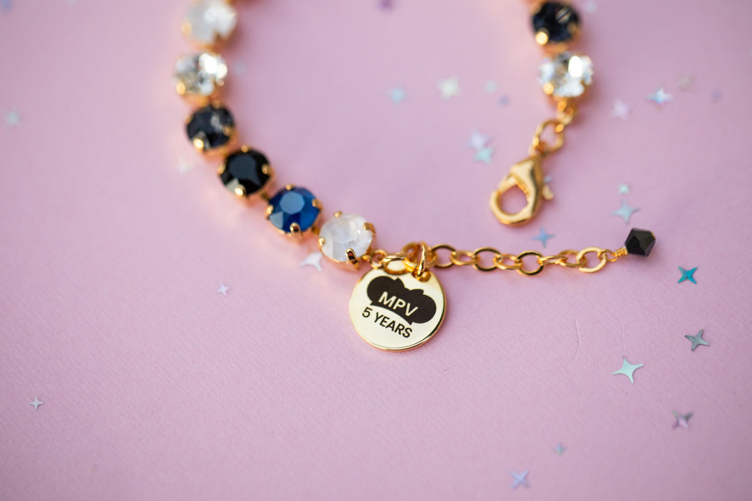 Bracelet with decorative beads and a heart-shaped tag on a pink background