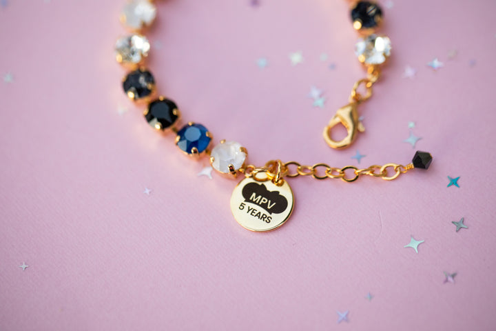 Bracelet with decorative beads and a heart-shaped tag on a pink background