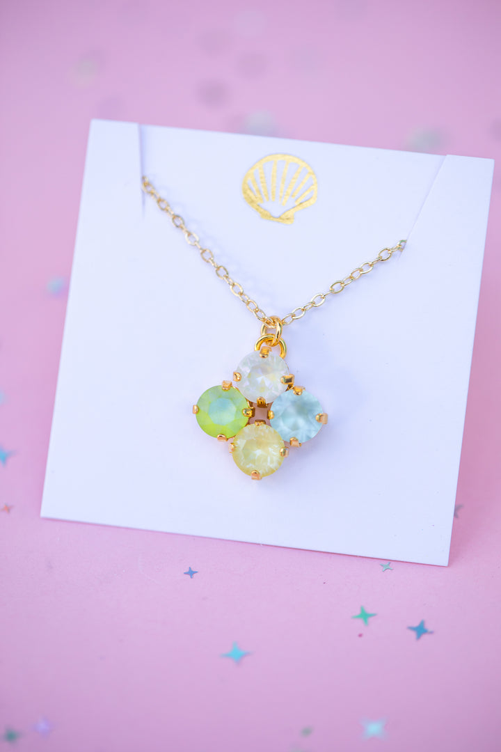 Necklace with colorful pendant on a white card against a pink background