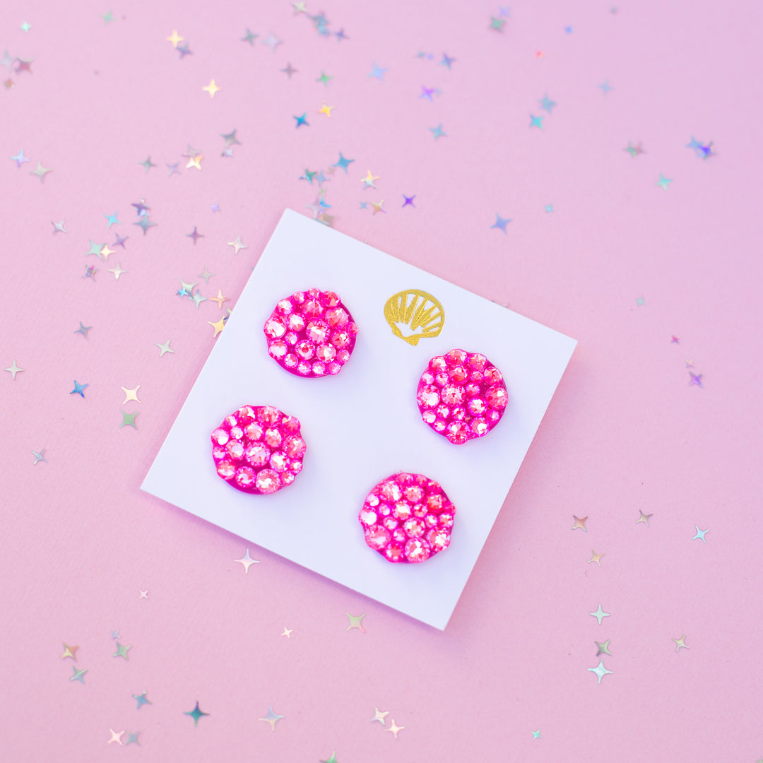 Four pink runner magnets with a gold shell on a white card against a pink background with star confetti.