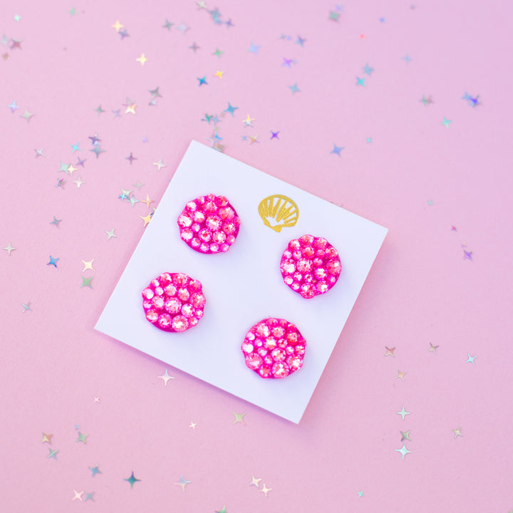 Four pink runner magnets with a gold shell on a white card against a pink background with star confetti.