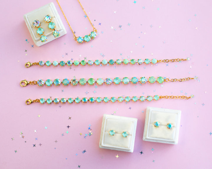 Jewelry set including bracelets, necklaces, and earrings on a pink background