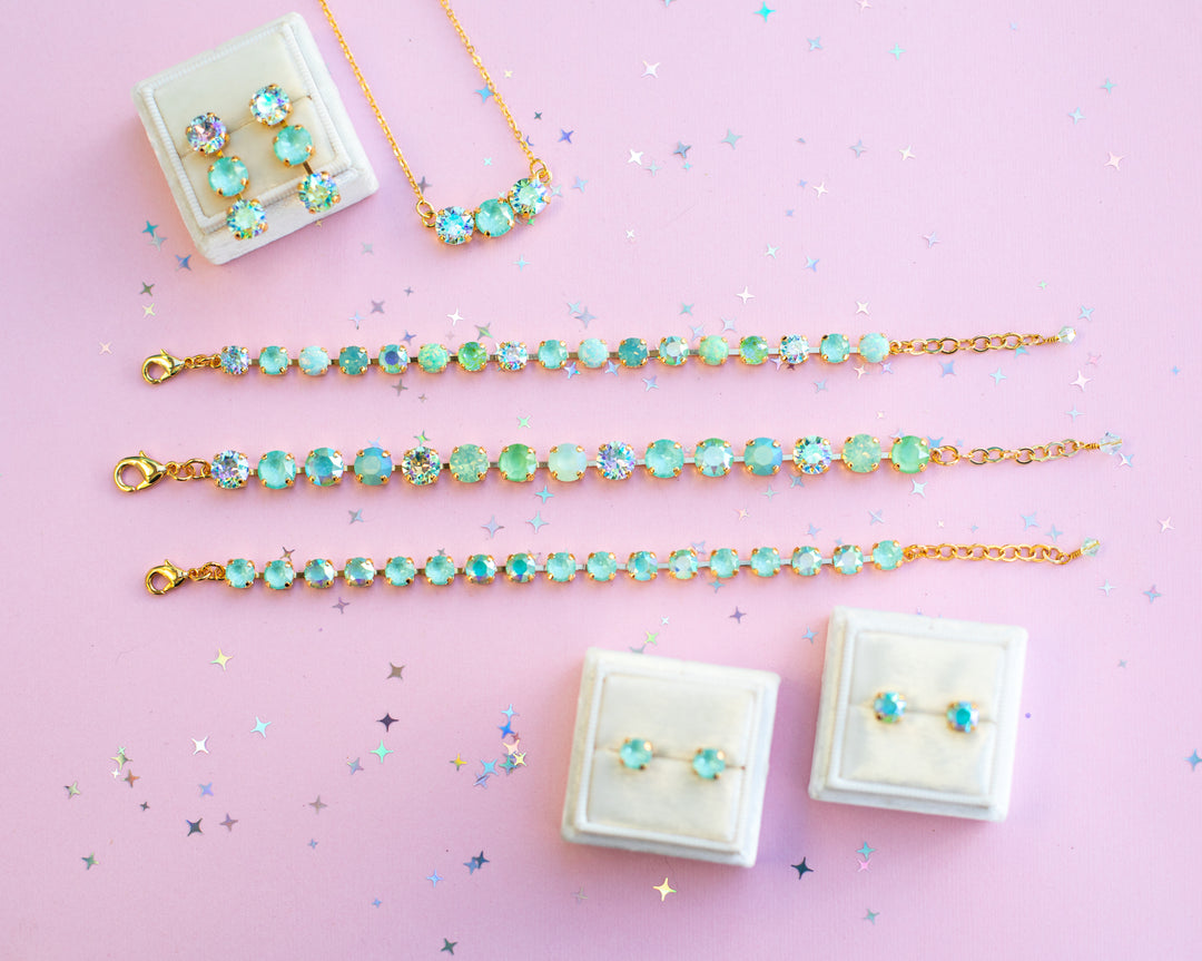 Jewelry set including bracelets, necklaces, and earrings on a pink background