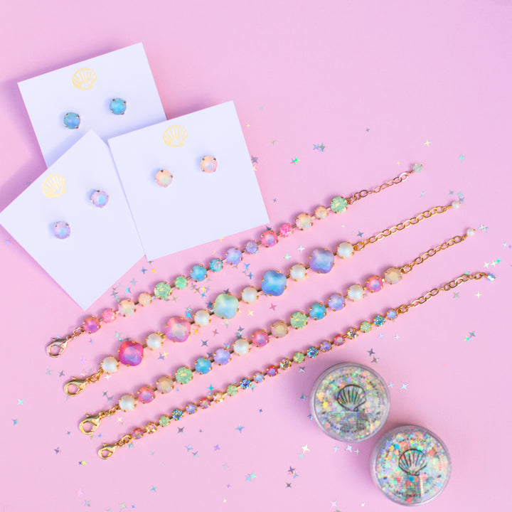 Colorful bracelets and earrings on a pink background