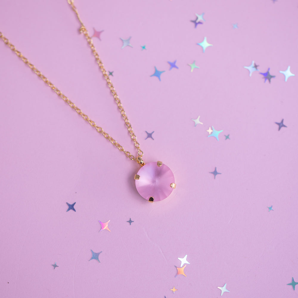 Necklace with a pink pendant on a purple background with star-shaped confetti