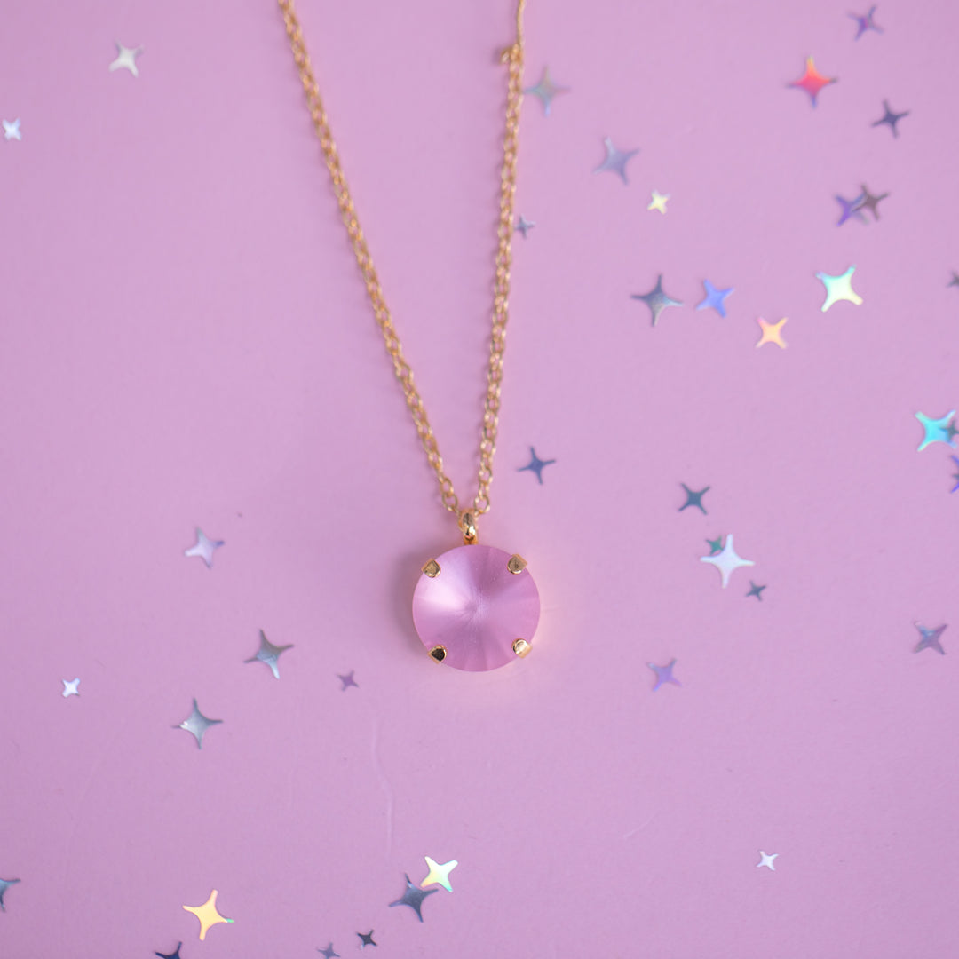 Necklace with a pink pendant on a pink background with star-shaped confetti